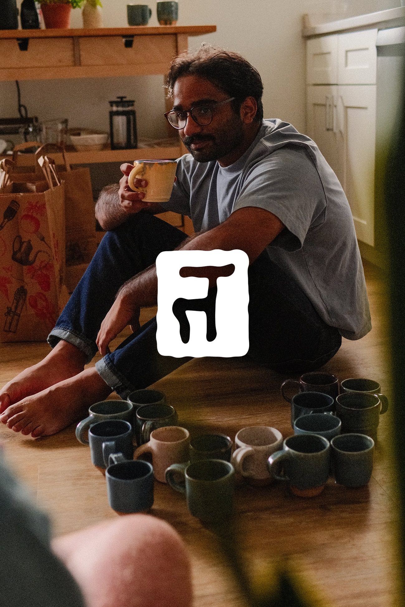 Tanay holding a mug, surrounded by the full set on the floor